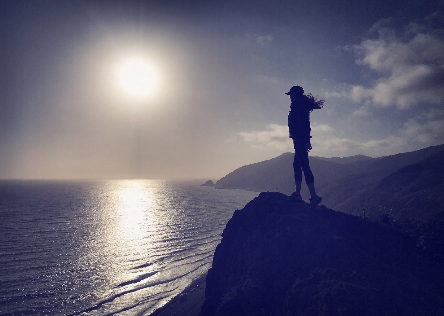 A person standing in front of a mountain Description automatically generated